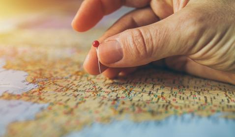 A hand putting a pin in a map.