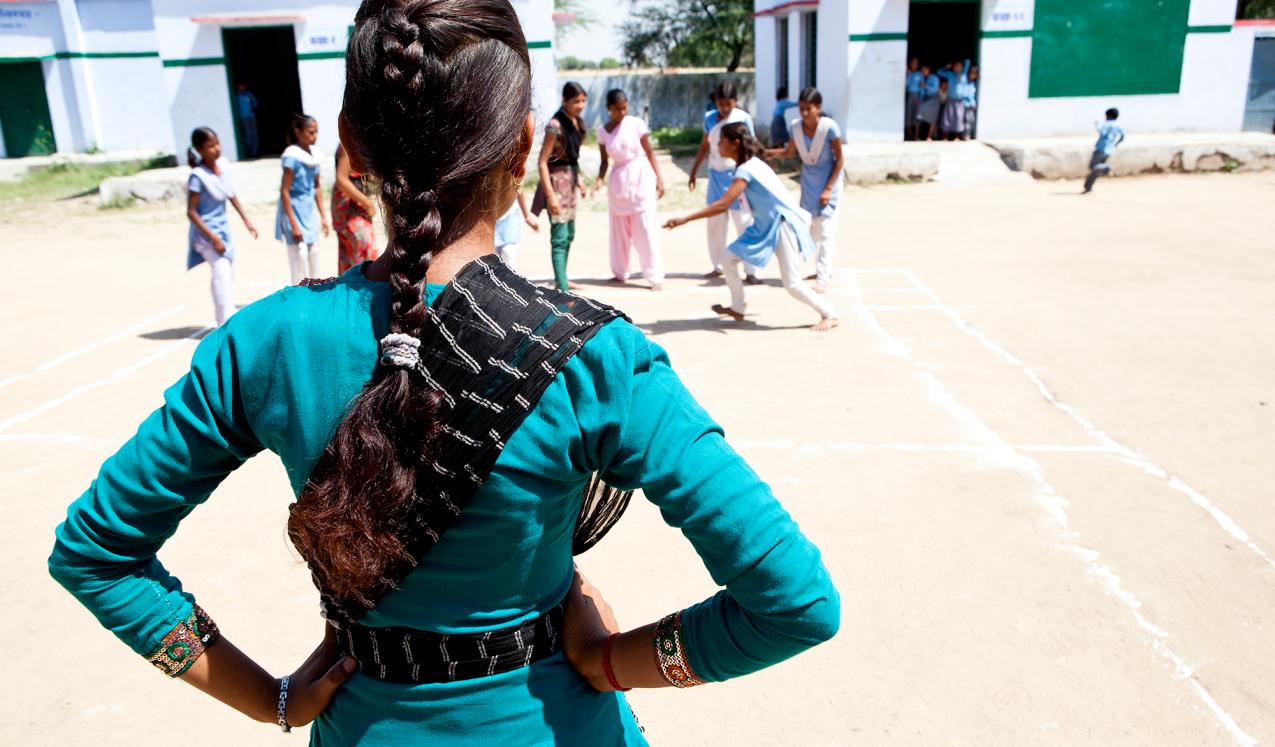 The back of a school girl in India looking at her friends in the playground. Credit: Charlotte Anderson