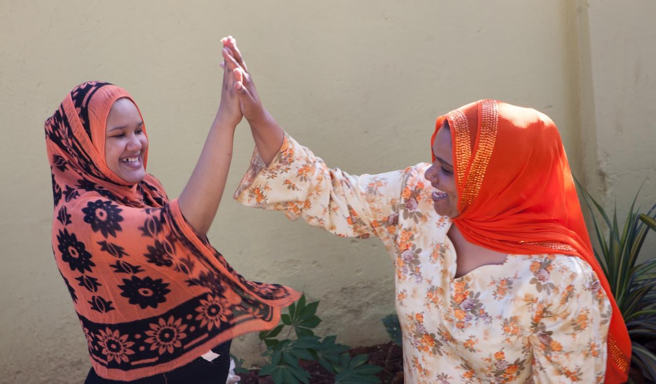 Two women 'high five-ing' © Raising Voices