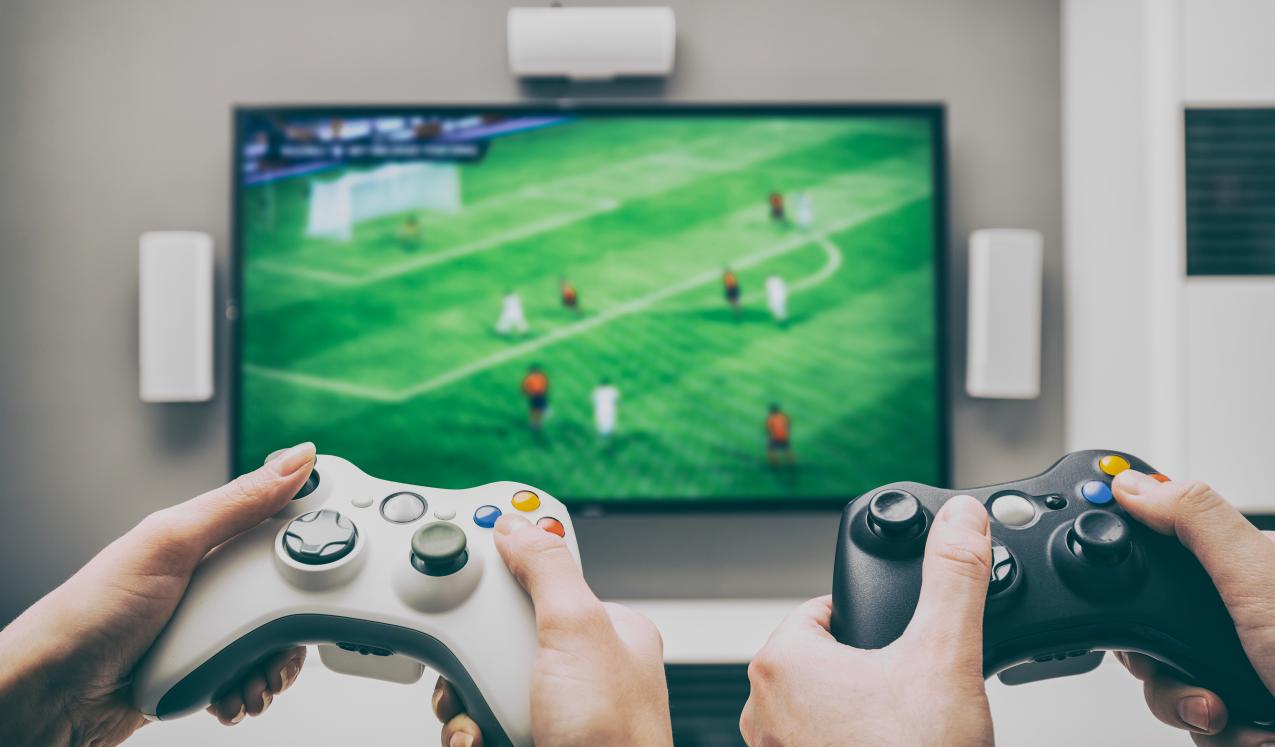 Hands operating video game controllers playing a football-base game. © REDPIXEL/shutterstock 537529714