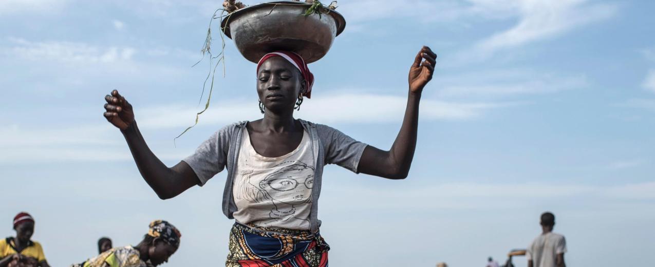 A woman distributes cassava cuttings while others plant them on on July 12, 2017 in Nigeria. © STEFAN HEUNIS/AFP/Getty Images