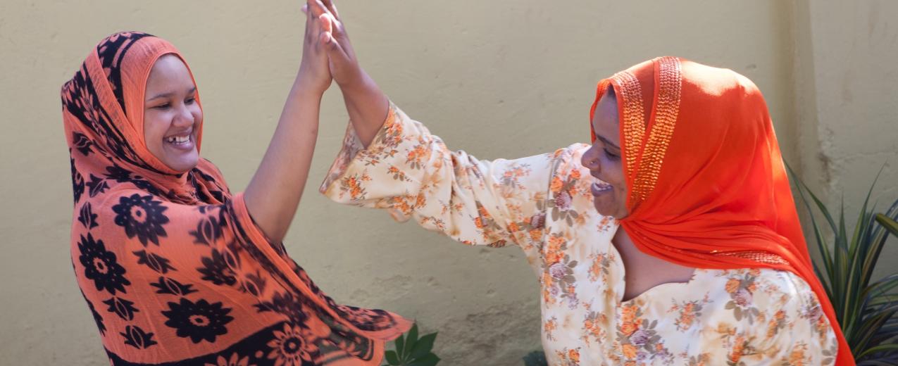 Two women 'high five-ing' © Raising Voices