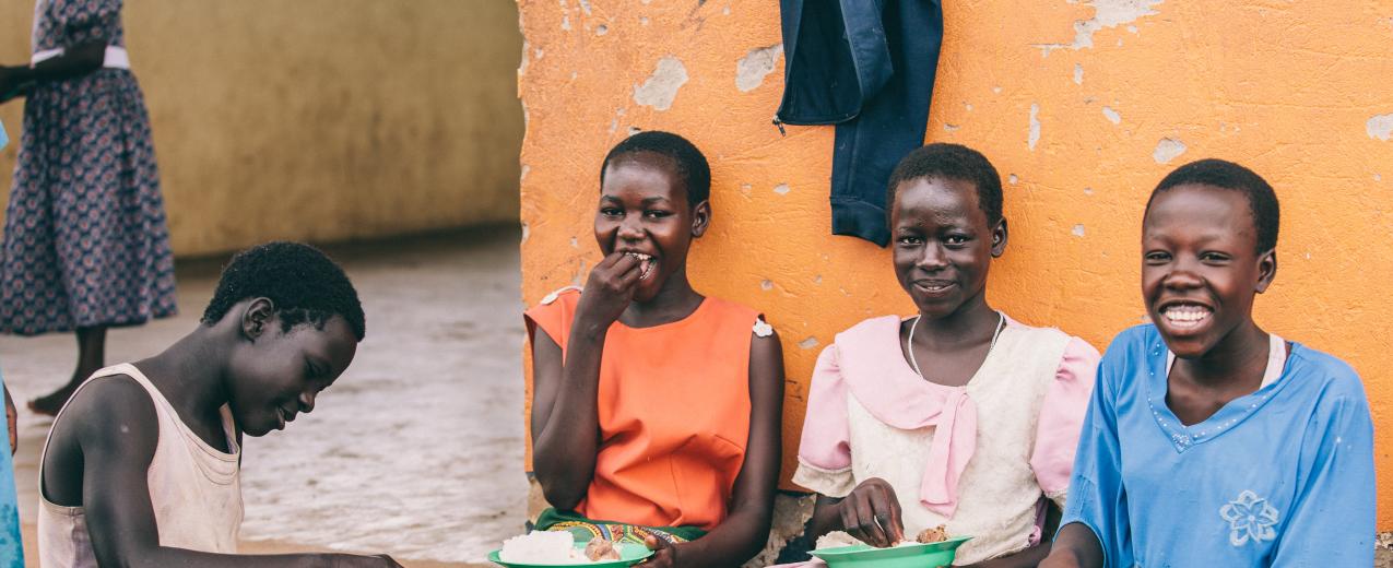 Lucy Agweto (far left), Christine Akwaso (far right), and their peers enjoy a meal together in Oditel, Uganda. © Brian Wolfe