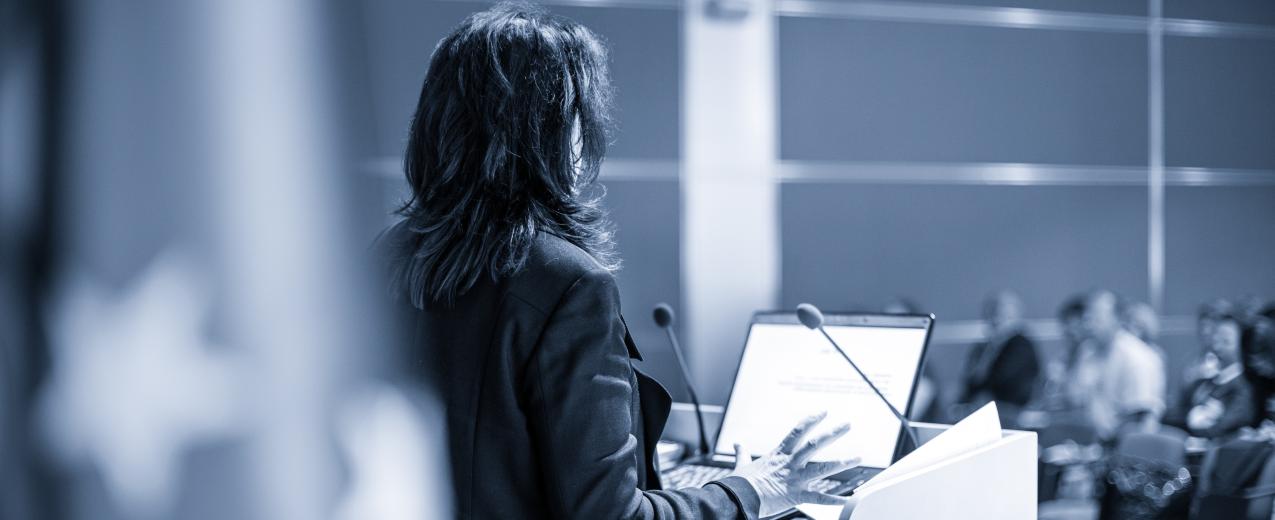 A female speaker at a conference ©Matej Kastelic / Shutterstock ID: 1156310920