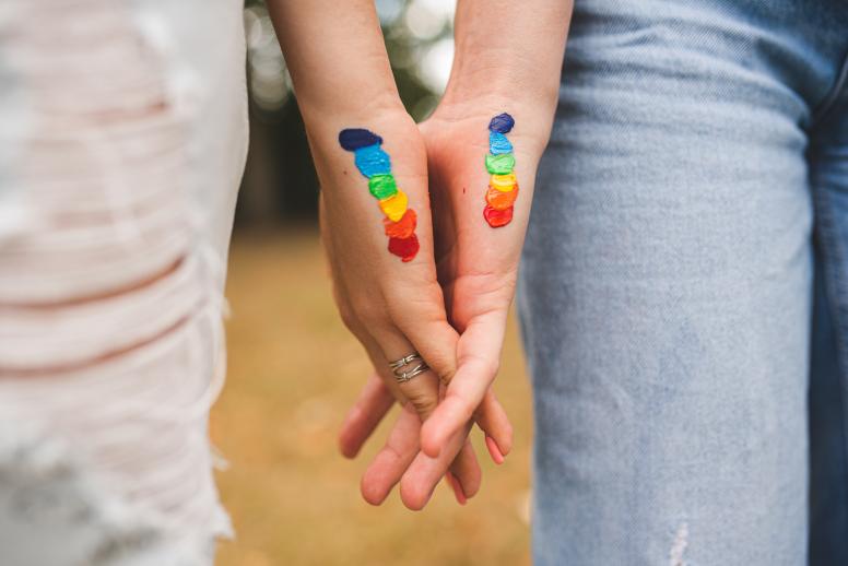 A couple holding hands with the LGBTQI+ flag painted on their palms. © Vera Moklyak | Shutterstock ID: 2198494757